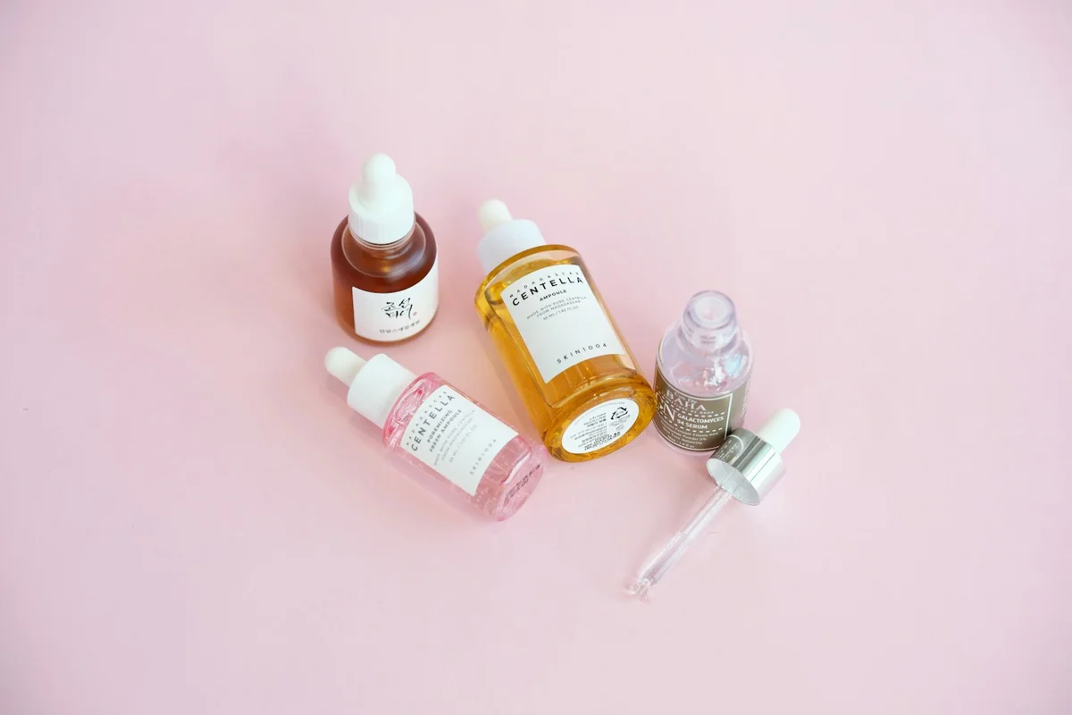 Skincare bottles arranged on a soft pink surface